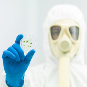 person in protective suit holding microorganism sample